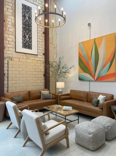 a living room with couches and chairs and a chandelier at Fyrebird Place - Industrial Loft with Pavilion & Yard in San Antonio