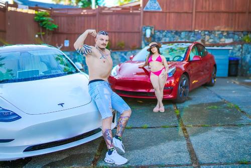 a shirtless man and a woman standing next to a white car at Illuminati Guest House in Victoria