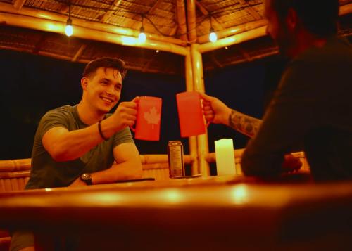 a man sitting at a table drinking from a red cup at Illuminati Guest House in Victoria