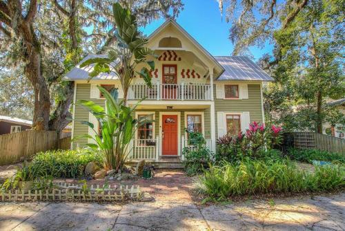 een geel huis met een rode deur en bomen bij Private Luxury Cottage Close to Downtown in St. Augustine