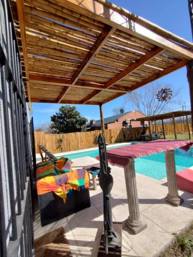 a patio with a wooden pergola next to a pool at Hermosa Casa con piscina in Carlos Keen