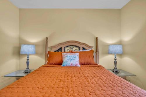 a bed with an orange bedspread and two lamps at Casa Dell'Amore in Murdock