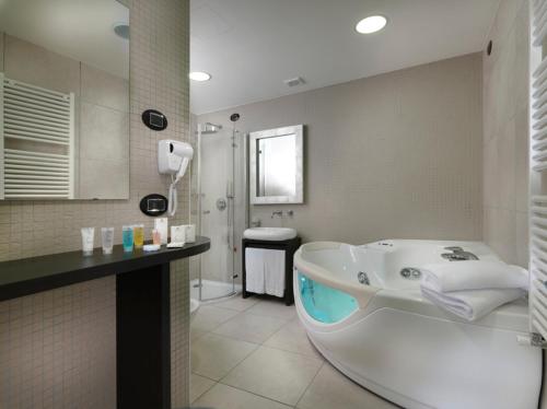 y baño con bañera grande y ducha. en Blu9 Hotel, en Novedrate