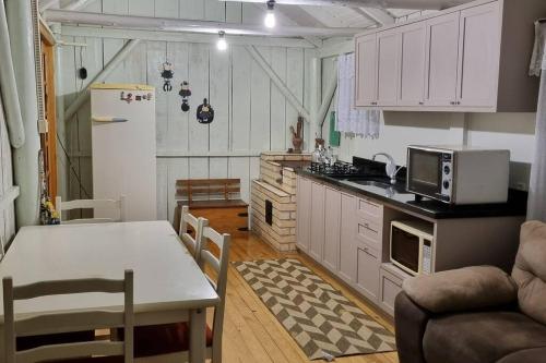 eine Küche mit weißen Schränken, einem Tisch und einem Esszimmer in der Unterkunft Casa de campo Campo Alegre SC 11 Hóspedes in Campo Alegre