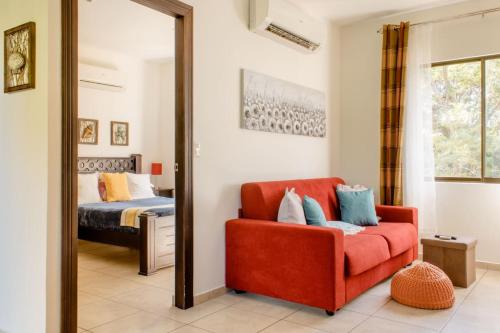 a living room with a red chair and a bed at Green Villas Tamarindo in Tamarindo