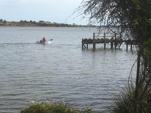 a person in a boat on the water next to a dock at Goolwa Retreat in Goolwa North