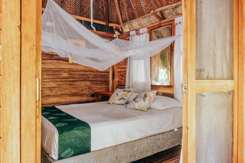a bedroom with a bed with a mosquito net at Magic Green Dentro del Parque Tayrona in El Zaino