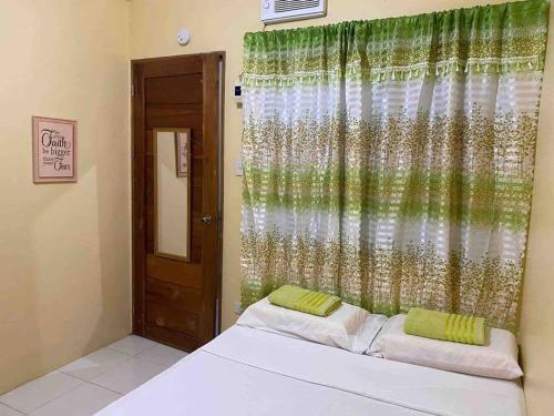 a bedroom with a bed with a green curtain at DaLei Suites in Pamplona in Tambojangin