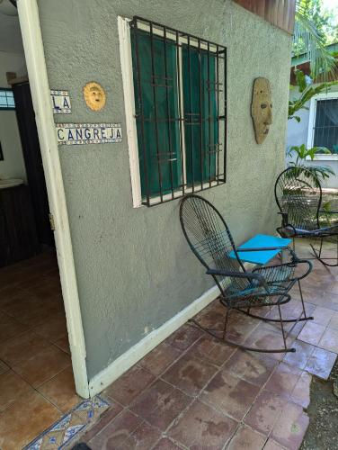 a door to a building with a chair and a window at Tasty Dayz Hostel in Puerto Viejo