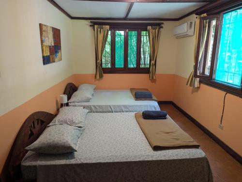 two twin beds in a room with windows at Tasty Dayz Hostel in Puerto Viejo
