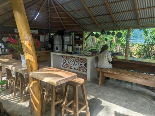 a woman sitting on a bench in a restaurant at Tasty Dayz Hostel in Puerto Viejo