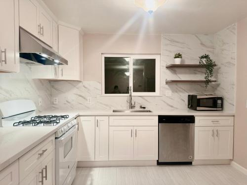 a white kitchen with a sink and a microwave at Nice and tranquil house 7 mins away from SFO in San Mateo