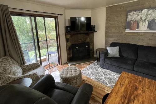 a living room with a black couch and a fireplace at Blue Spruce Condo #134 in Ruidoso