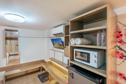 a small room with a microwave and a kitchen at โรงแรมชิบะรูม นครราชสีมา สาขามหาวิทยาลัยเทคโนโลยีสุรนารี in Nakhon Ratchasima