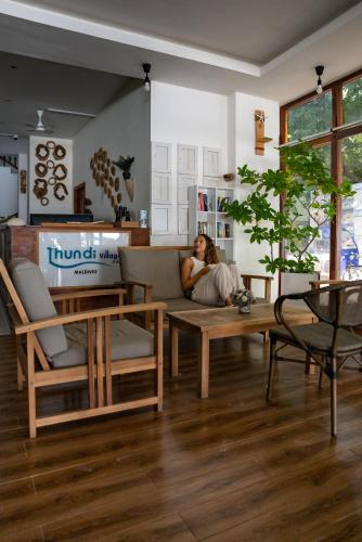 a woman sitting on a couch in a living room at Thundi Village & Spa in Maalhos