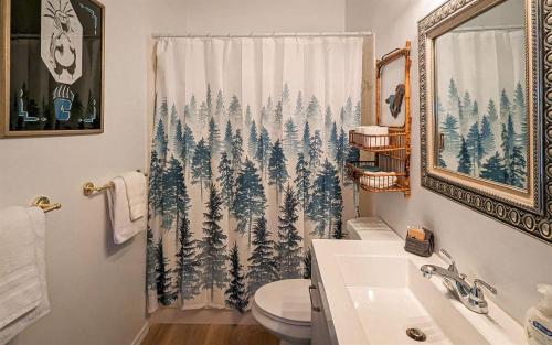a bathroom with a shower curtain with pine trees at Mama Bears Cabin in Ruidoso