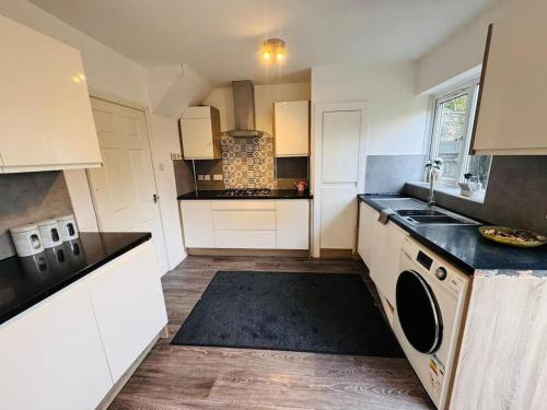 a kitchen with white cabinets and black counter tops at 3 Bedroom Modern House in Luton LU4 0TY - Amazon Prime - No Party in Luton