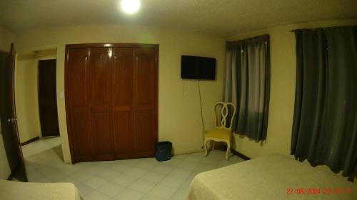 a bedroom with a bed and a door and a chair at Hotel San Antonio Guanajuato in Guanajuato