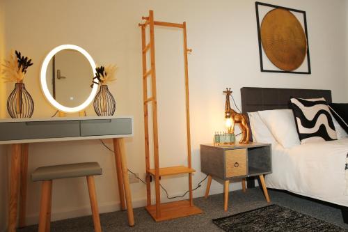 a bedroom with a bed and a mirror and a table at Luton Airport House, Opposite airport staff parking in Luton