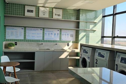 a laundry room with a washing machine and a table at Loft Elegante Centro in Dourados
