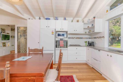 a kitchen with a wooden table and white cabinets at Sunset Villa Norfolk Island - a Mediterranean inspired villa in Burnt Pine