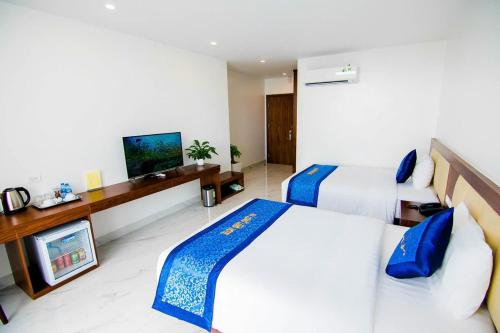 a hotel room with two beds and a flat screen tv at Hạ Long Land Hotel in Ha Long
