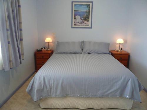 ein Schlafzimmer mit einem großen Bett mit zwei Nachttischen in der Unterkunft Jetty Views in Wauraltee