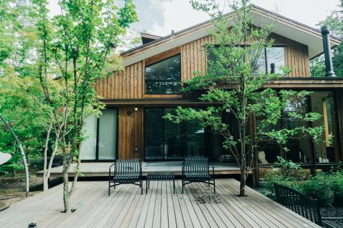 a house with two chairs on a deck at Karuizawa Forest Seasons Villa in Karuizawa