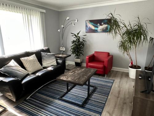 a living room with a black leather couch and a red chair at Spotless 2 Bedroom Suite in Winnipeg in Winnipeg