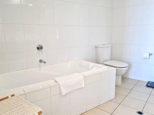 a white bathroom with a tub and a toilet at Glam Apartment 21 in Wallaroo