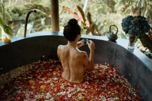 a shirtless boy sitting in a large bowl of flowers at Maha Hills Resort by Mahaprana Experience in Lovina