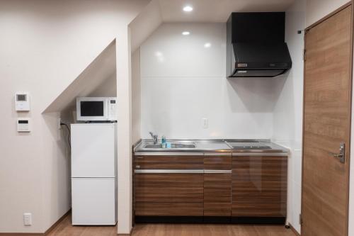 a small kitchen with a sink and a refrigerator at 鱗町庵 in Kanazawa