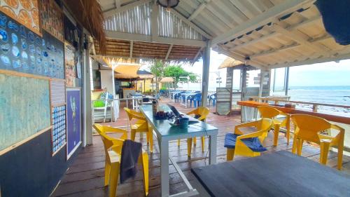 a restaurant with yellow chairs and tables and the ocean at Kohchang 7 seaview bungalow in Ko Chang
