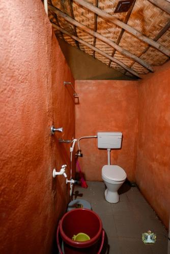 a bathroom with a toilet and a red wall at Hampi Waterfall Cottages in Hampi