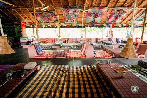 a room with lots of couches and pillows at Hampi Waterfall Cottages in Hampi