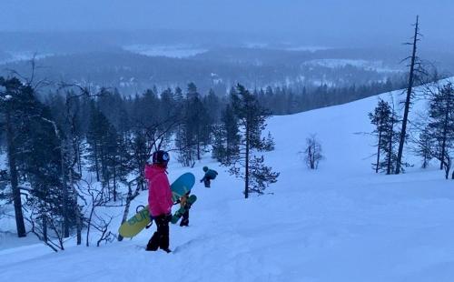 a person holding a snowboard on a snow covered slope at Arctic Lodges Lapland Ski In Family Studio, Wi-Fi, National Park - Lapland Villas in Pyhätunturi