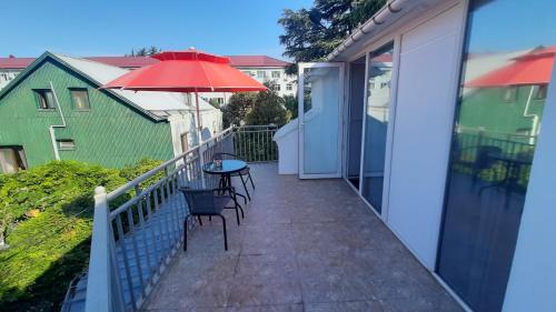 a balcony with a table and an umbrella at Guesthouse Next to beach in Batumi