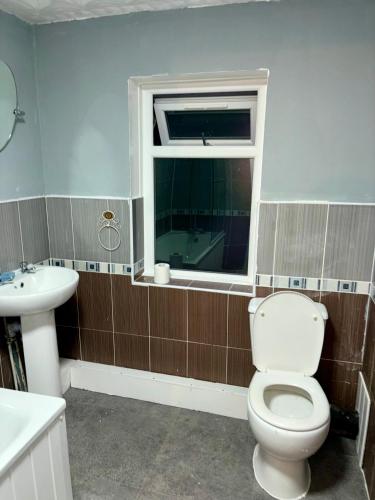 a bathroom with a toilet and a sink and a window at Stainless Guests house in Dudley