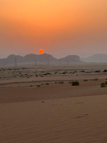 a sunset in the desert with the sun setting at Radisson Wadi Rum Camp in Wadi Rum
