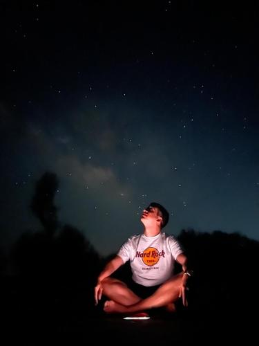 a man sitting on the ground looking up at the night sky at Radisson Wadi Rum Camp in Wadi Rum