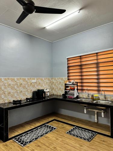a kitchen with a sink and a ceiling fan at Homestay De Acacia Rumah Melati in Kuala Terengganu