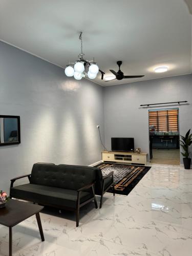 a living room with a couch and a tv at Homestay De Acacia Rumah Melati in Kuala Terengganu