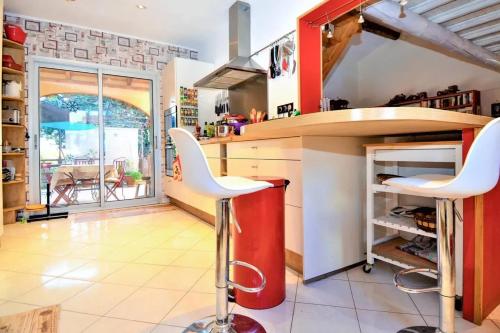 une cuisine avec un comptoir rouge et des tabourets blancs dans l'établissement Villa envoûtante à Eyragues avec piscine, à Eyragues