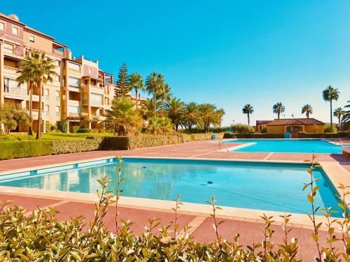 a large swimming pool with palm trees and buildings at Alcaudón, Isla Canela - By AC REAL in Isla Canela