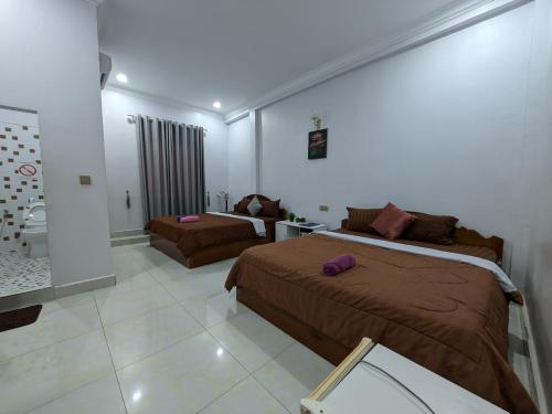 a bedroom with two beds and a living room at Orchid 101 in Kampot