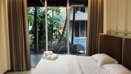 a bedroom with a bed and a large window at Waves By Jumbo Holidayz in Alibag