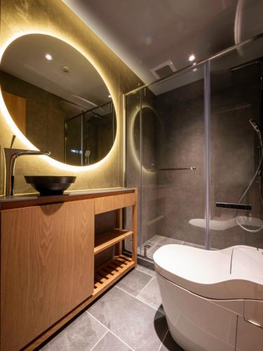 a bathroom with a tub and a sink and a mirror at Ski Inn Hakuba, Iwatake in Hakuba