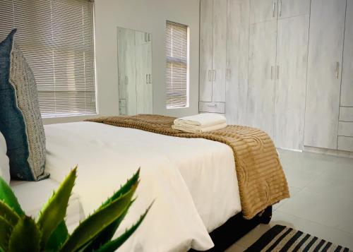 a bedroom with two beds and a plant at Olive Villa Self Catering Apartments in Swakopmund