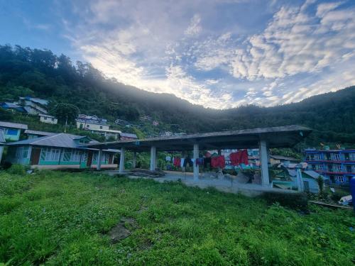 a building on a hill with a town in the background at Neoravalley Homestay, Icche Gaon in Pedong