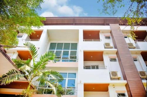 an apartment building with windows and a palm tree at Srivara Place โรงแรมศรีวรา เพลส in Phetchabun